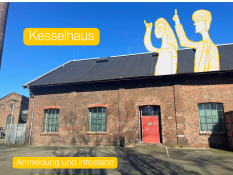 Auf dem Bild sieht man ein altes Backstein‑Gebäude. Es hat große Fenster und eine rote Tür. Über dem Gebäude ist ein blauer Himmel. Auf dem Dach sind zwei gezeichnete Figuren zu sehen. Auf dem Bild stehen die Wörter „Kesselhaus“ und „Anmeldung und Infostand“ in gelben Kästen.