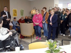 Im Projektbüro stehen mehrere Menschen mit und ohne Behinderung aus dem Netzwerk und hören dem Kulturdezernent der Stadt Oberhausen Apostolos Tsalastras zu. Bei dieser Veranstaltung handelt es sich um die Büroeröffnung von Lass‘ mal gemeinsam machen.